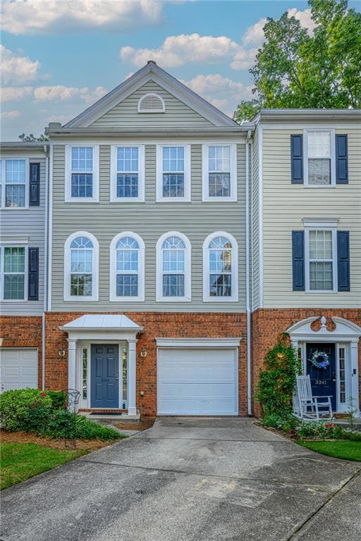 Townhome / multi-family property with concrete driveway, an attached garage, and brick siding