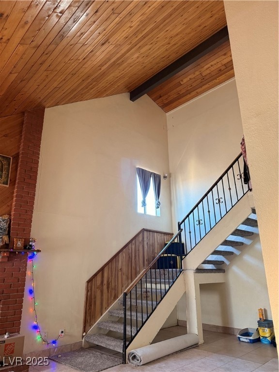 Stairs featuring a wooden ceiling with exposed beams, high vaulted ceiling, and tile patterned floors