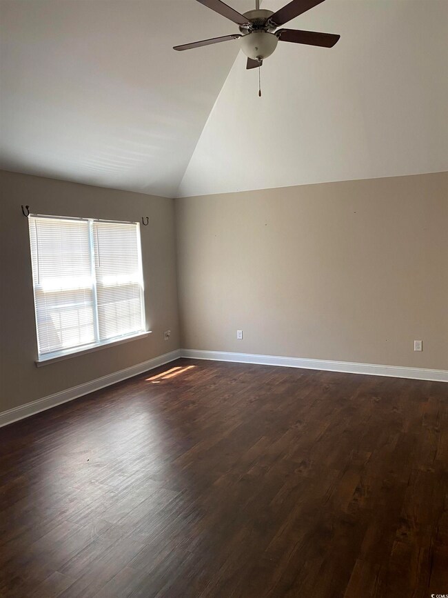 Empty room featuring ceiling fan, vaulted ceiling,