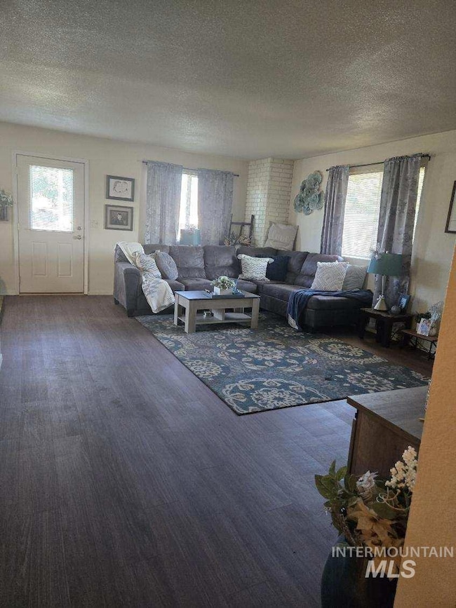Living area featuring a textured ceiling, plenty of natural light, and wood finished floors