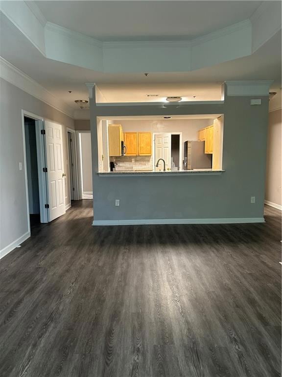 Unfurnished living room with ornamental molding, a tray ceiling, and dark wood-type flooring