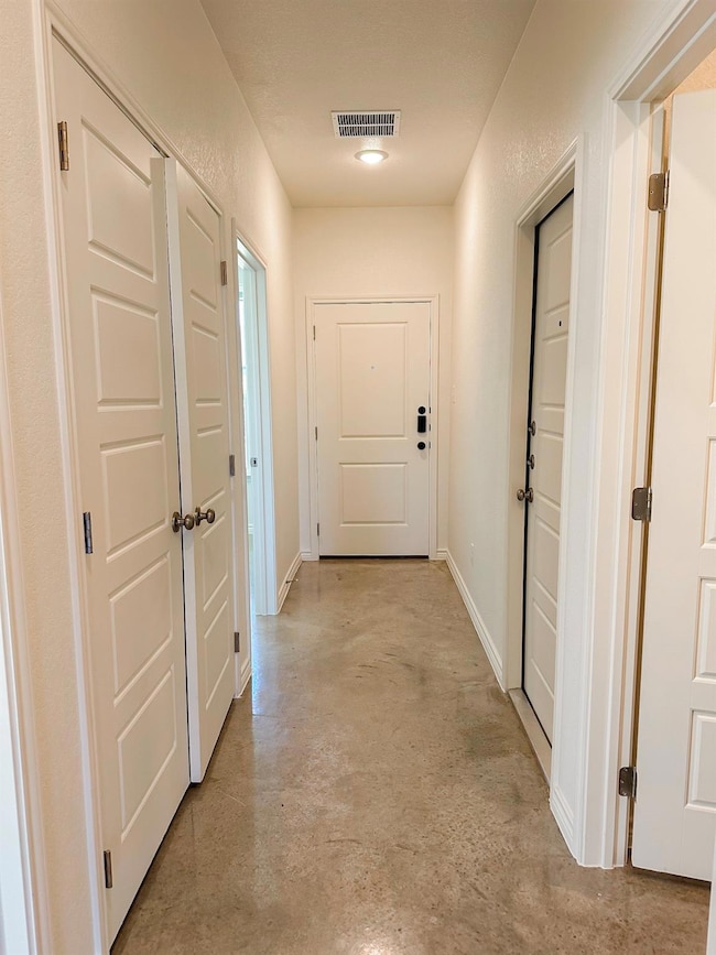 Corridor featuring concrete flooring and baseboards