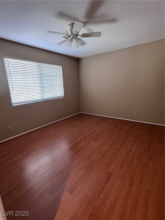 Empty room with dark wood finished floors and ceiling fan