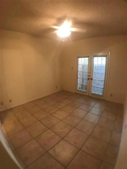 Unfurnished room featuring french doors, light ti