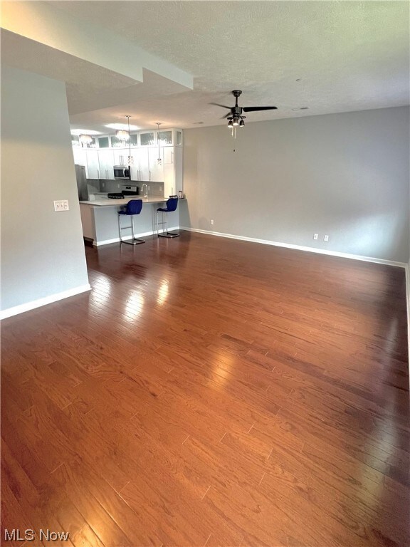 Unfurnished living room featuring sink, ceiling fan, and hardwood / wood-style flooring