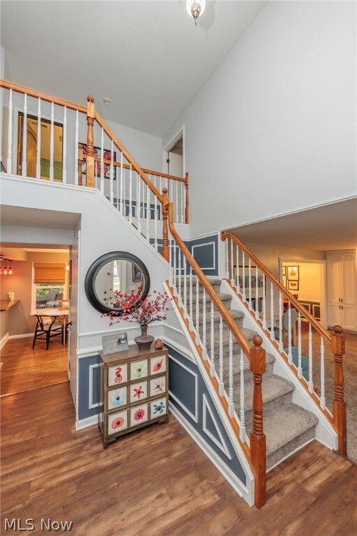 Stairway featuring a towering ceiling and hardwood / wood-style floors