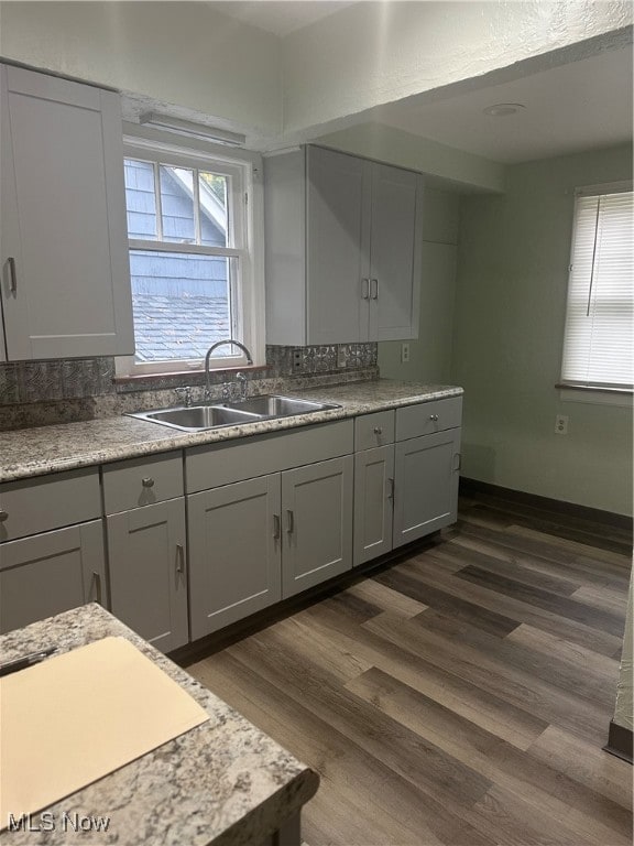 Kitchen featuring gray cabinetry, dark wood-style floors, and light stone counters