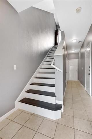 Stairway with baseboards and tile patterned floor