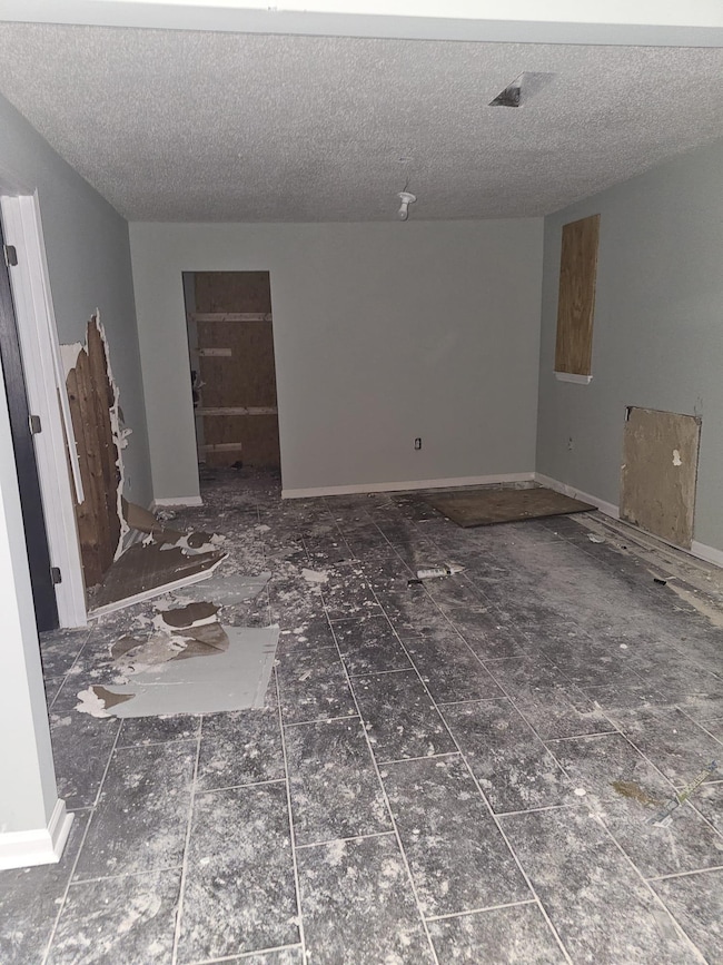 Unfurnished room with a textured ceiling and baseboards