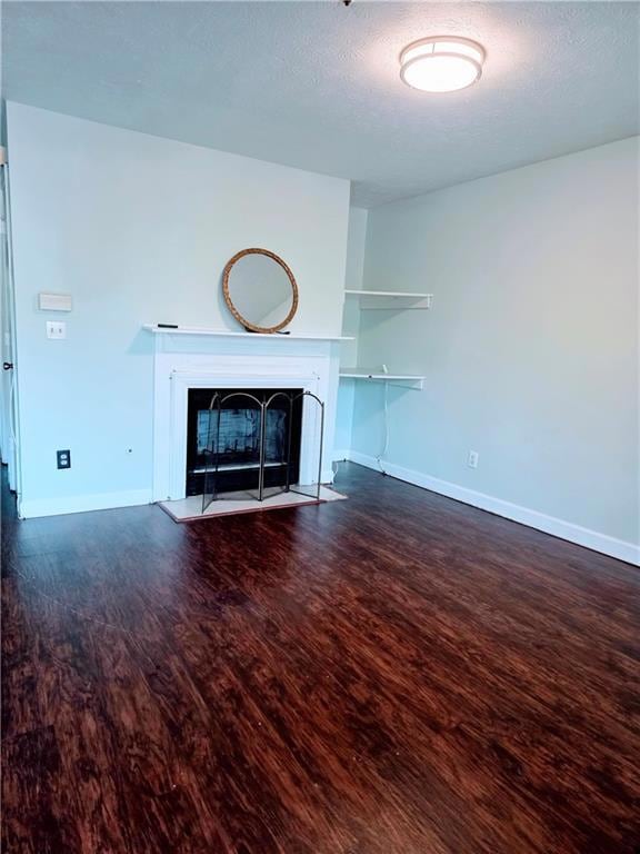 Unfurnished living room featuring a fireplace, dark wood-style floors, and a textured ceiling