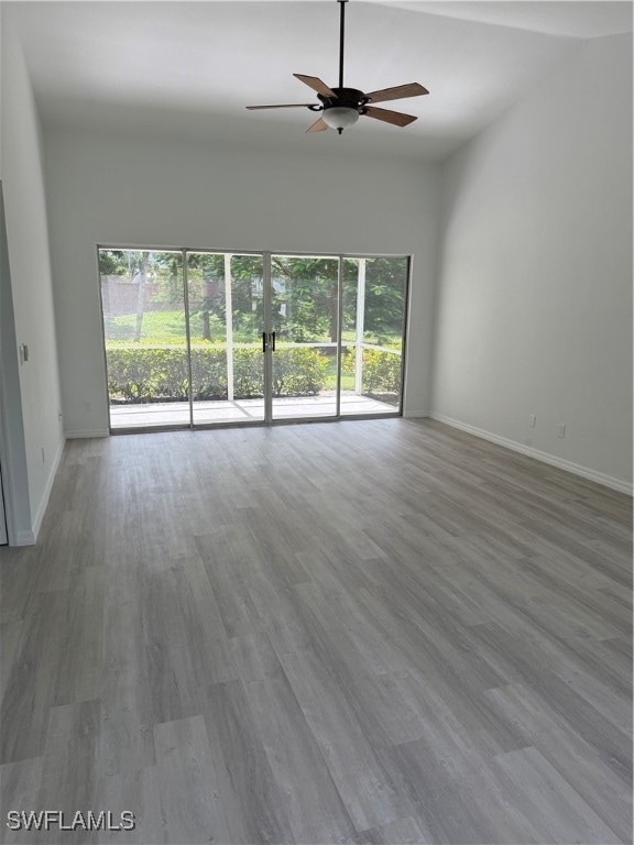 Unfurnished living room featuring light wood-style floors, plenty of natural light, ceiling fan, and vaulted ceiling