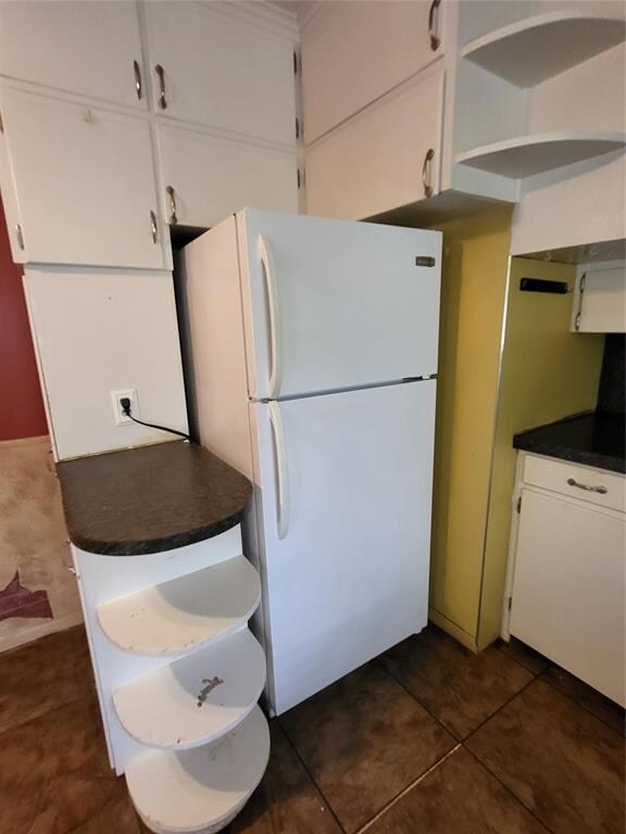Kitchen with dark tile floors, white cabinets, and