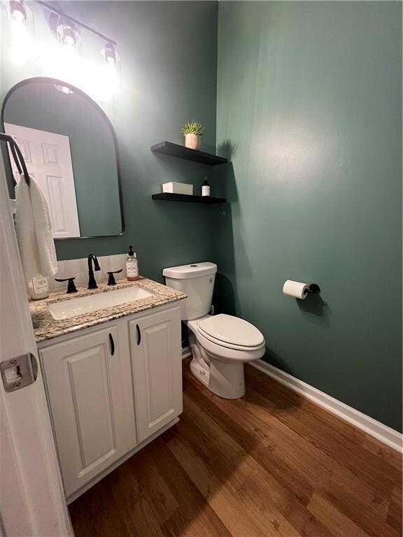 Bathroom with wood finished floors, vanity, toilet, and baseboards