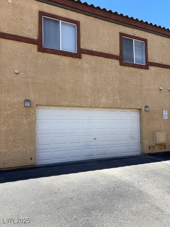 View of side of home with a garage and stucco sidi