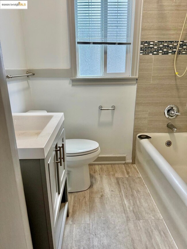 Bathroom featuring vanity, washtub / shower combination, and wood finished floors