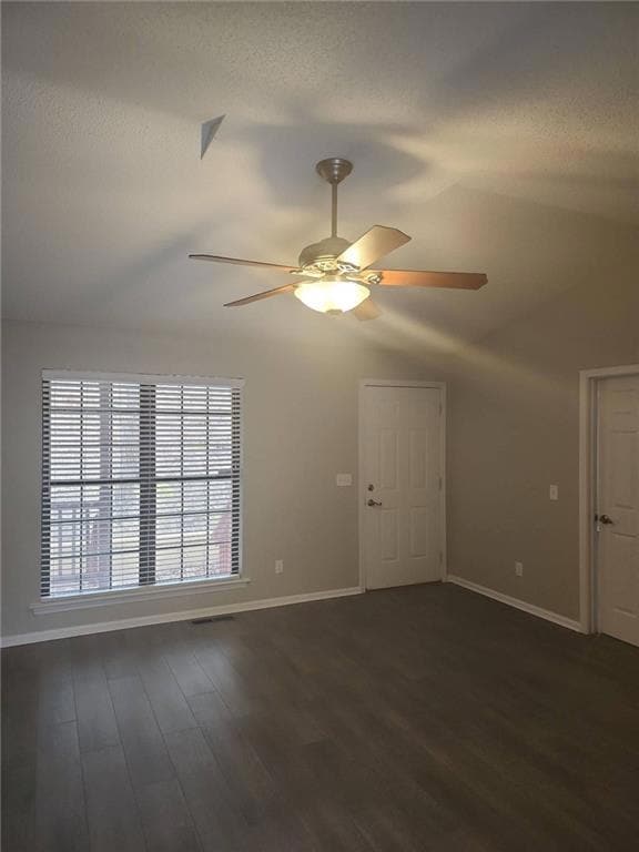 Unfurnished room with lofted ceiling, dark wood finished floors, ceiling fan, and a textured ceiling