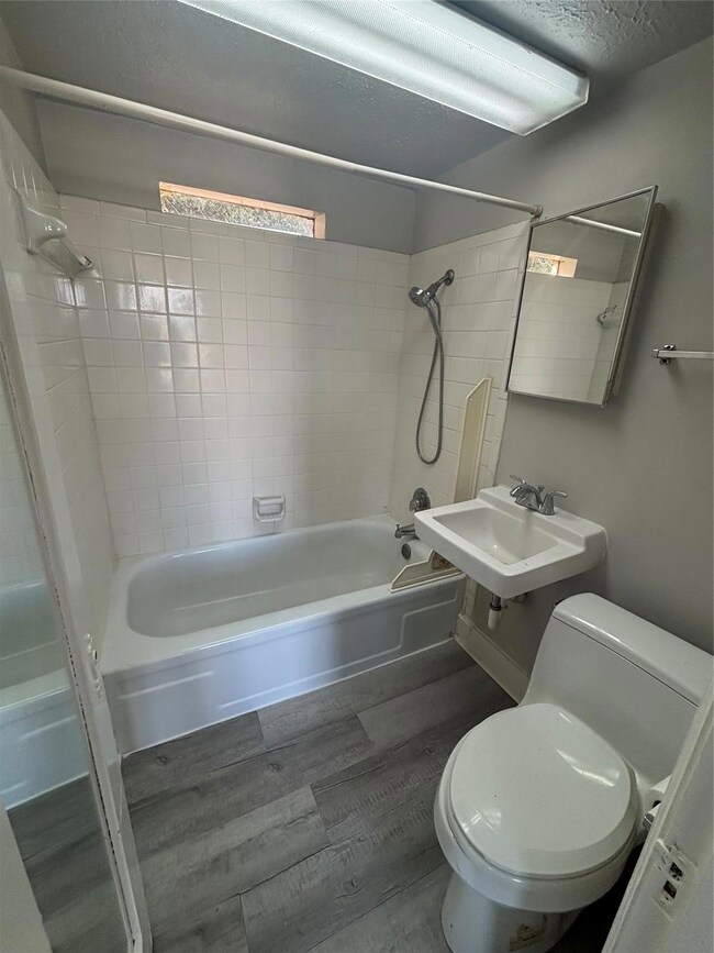 Full bathroom with toilet, tiled shower / bath, hardwood / wood-style flooring, and sink