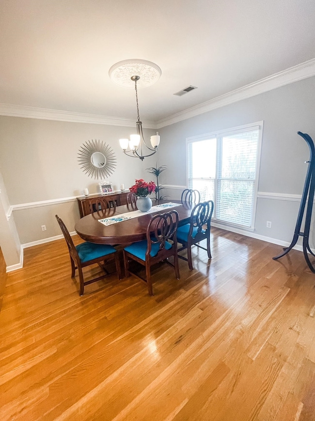Dining space featuring hardwood / wood-style flooring, an inviting chandelier, and crown molding