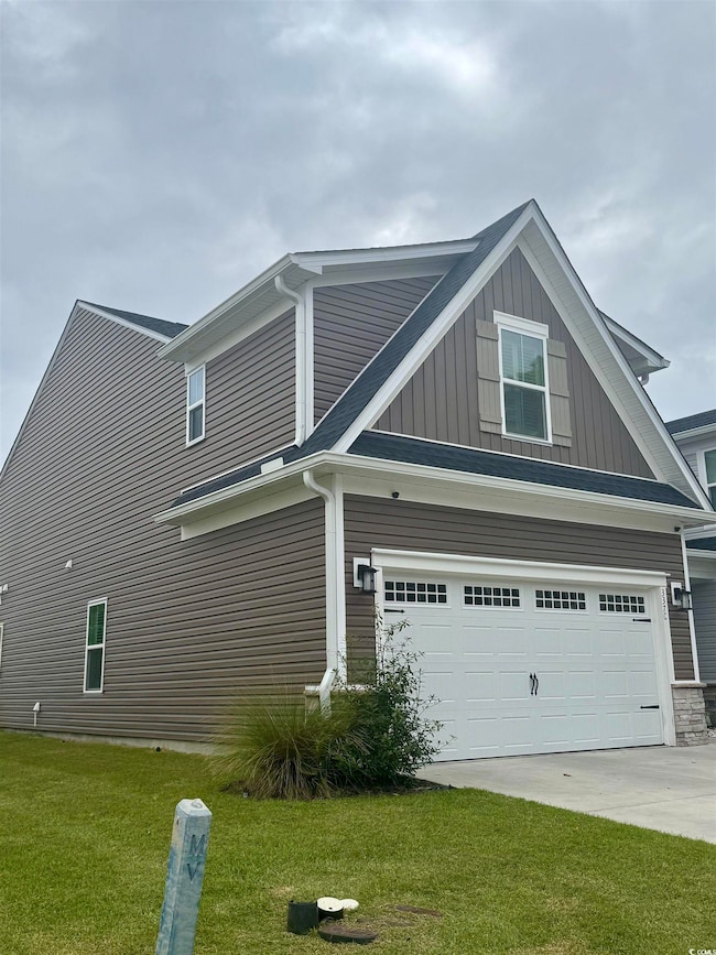 View of home's exterior with an attached garage, concrete driveway, a yard, and board and batten siding