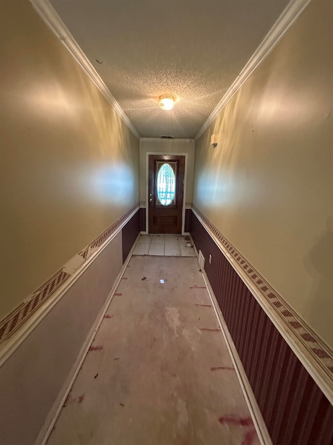 Doorway featuring a textured ceiling and crown molding