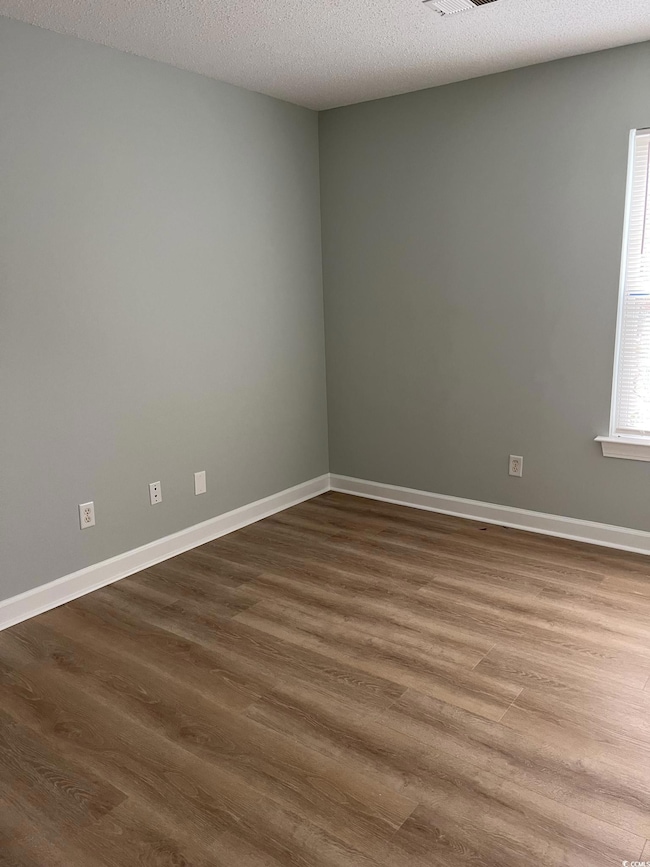 Unfurnished room featuring baseboards, dark wood-s