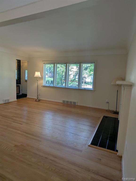 Unfurnished living room featuring light wood-style flooring and baseboards