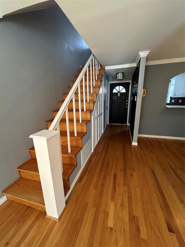 Entrance foyer featuring stairs, crown molding, wo