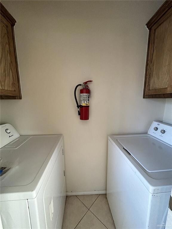 Washroom with cabinet space, baseboards, washing machine and dryer, and light tile patterned floors