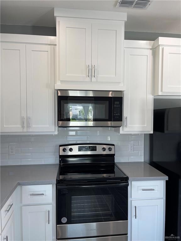 Kitchen with white cabinets, appliances with stainless steel finishes, and tasteful backsplash