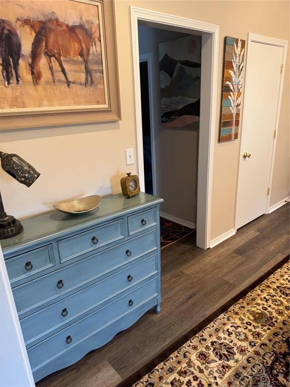 Hallway featuring dark wood finished floors and baseboards