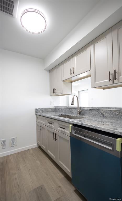 Kitchen with dishwasher, light stone countertops, and light wood finished floors