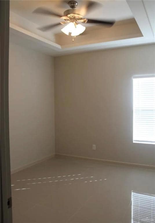 Tiled spare room with a tray ceiling and a ceiling fan