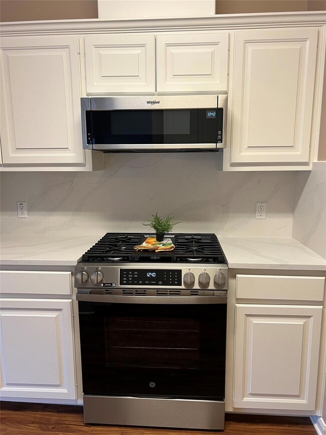 Kitchen with white cabinetry, appliances with sta