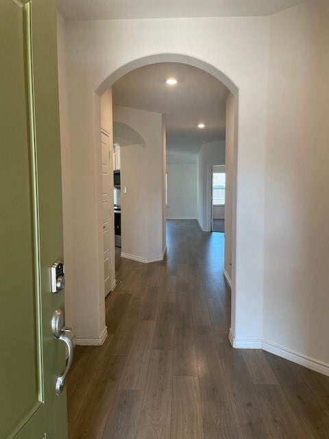 Corridor with dark wood-type flooring and arched walkways