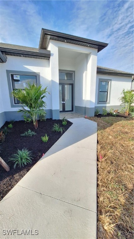 Doorway to property featuring stucco siding