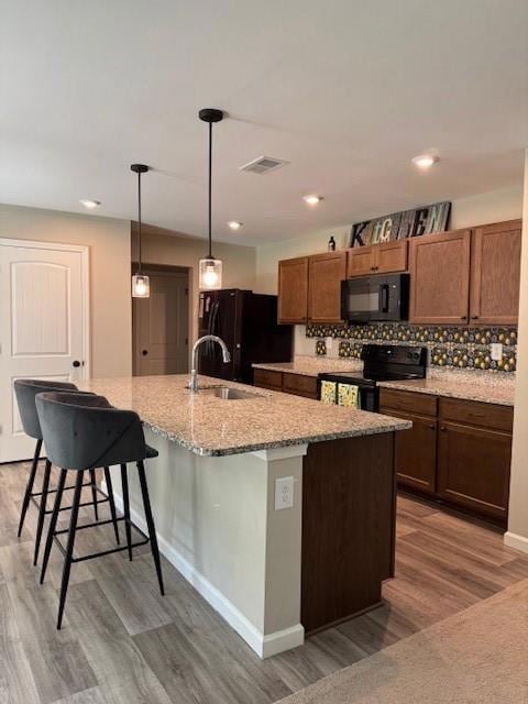 Kitchen with stove, light wood finished floors, a breakfast bar, freestanding refrigerator, and recessed lighting
