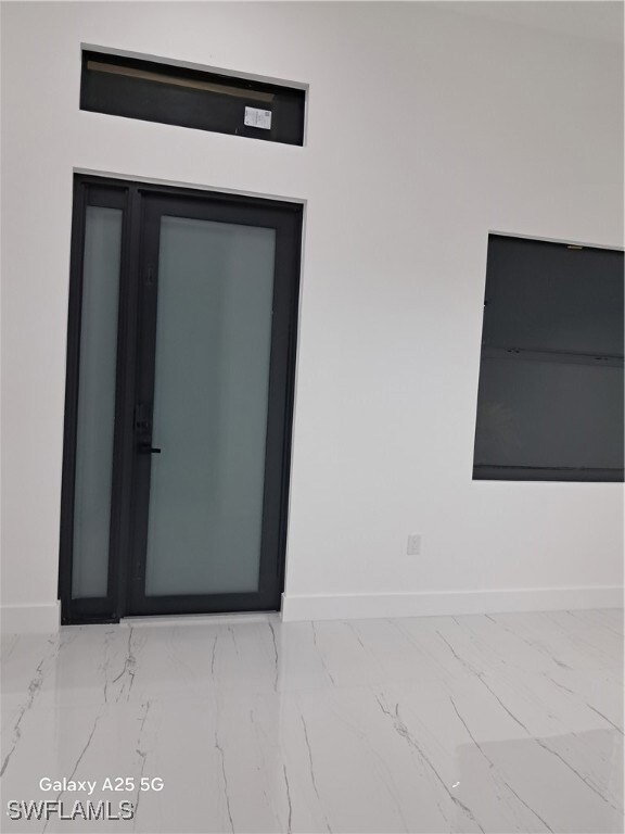 Spare room with baseboards and marble look tile fl