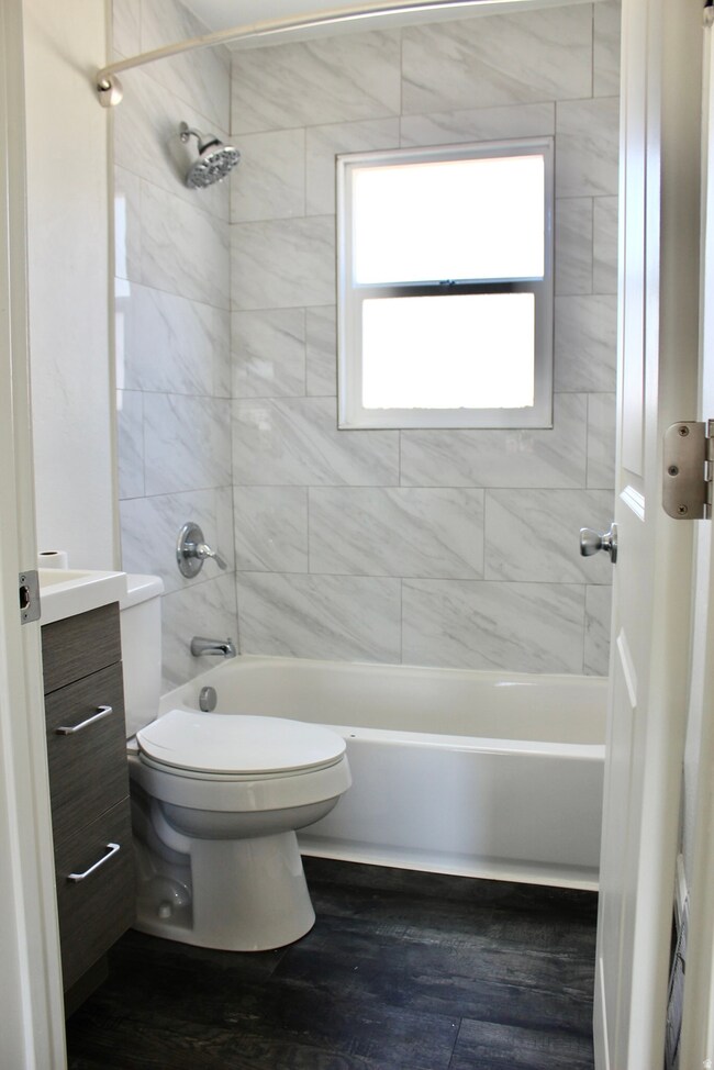 Bathroom with vanity, shower / washtub combination, and dark wood-type flooring