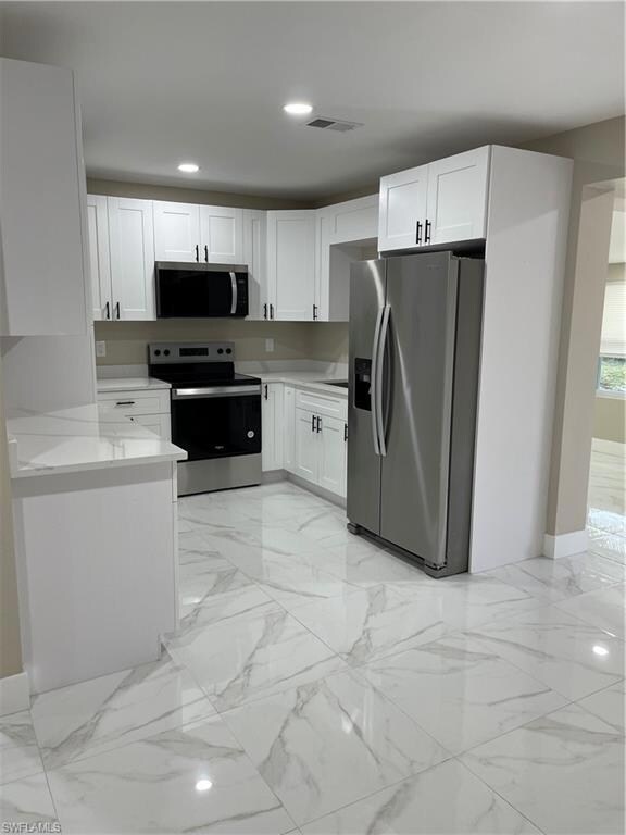Kitchen with light stone countertops, white cabine
