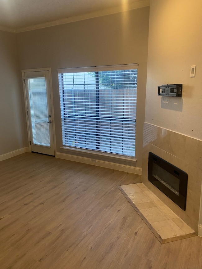 Unfurnished living room featuring wood finished floors, plenty of natural light, ornamental molding, and a fireplace