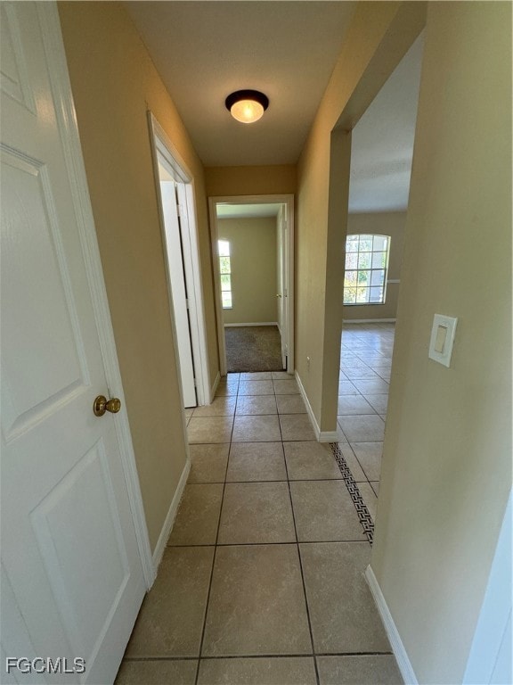 Hall featuring light tile patterned floors and plenty of natural light