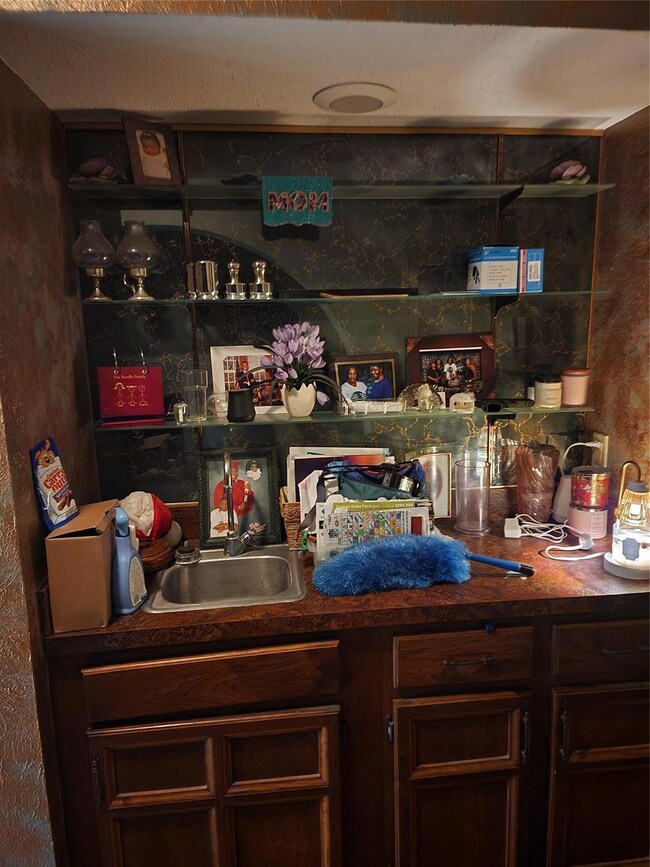 Bar with dark brown cabinetry and sink