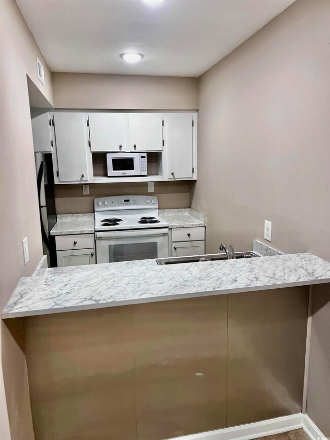 Kitchen featuring white cabinetry, kitchen peninsu