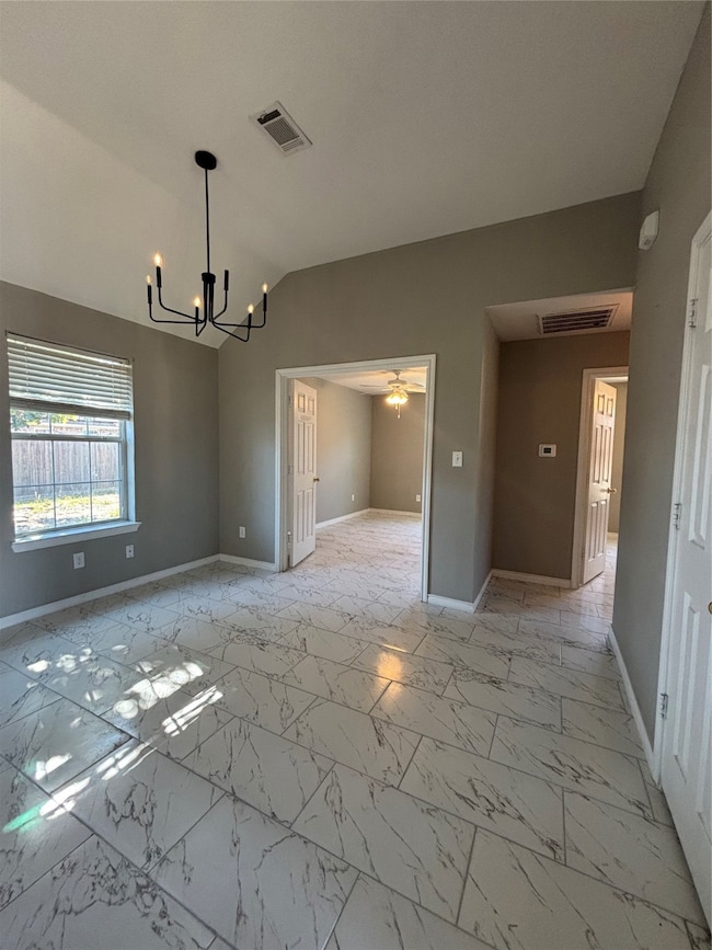 Spare room with a ceiling fan, light marble finish floors, lofted ceiling, and a chandelier