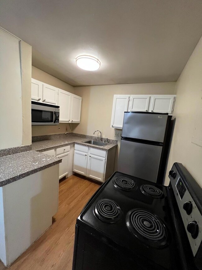Kitchen with white cabinets, light wood-style flo