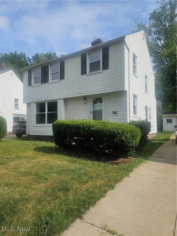 Colonial house featuring a front yard and a chimney