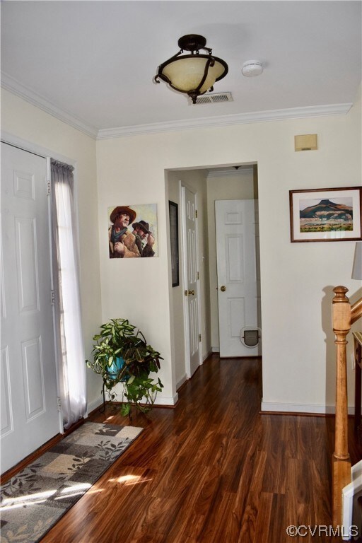 Foyer featuring dark hardwood flooring and crown m