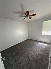 Empty room with ceiling fan and dark colored carpet