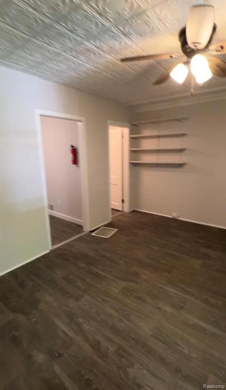 Unfurnished bedroom with dark wood finished floors, ceiling fan, a closet, and an ornate ceiling