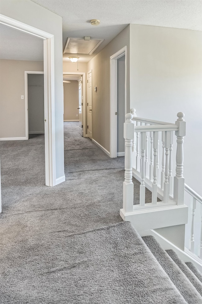 Hall with carpet floors, an upstairs landing, atti